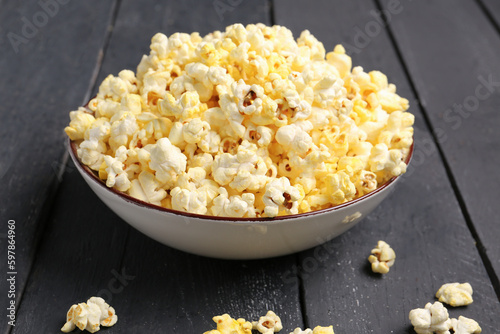 Bowl with crispy popcorn on dark wooden background