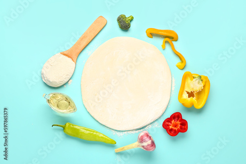 Raw dough and ingredients for preparing vegetable pie on blue background