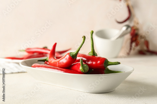 Plate of fresh chili peppers on light background