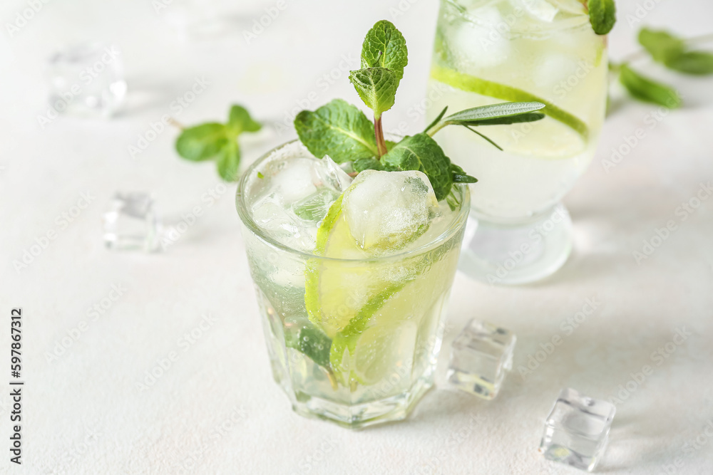 Glass of tasty mojito on light background