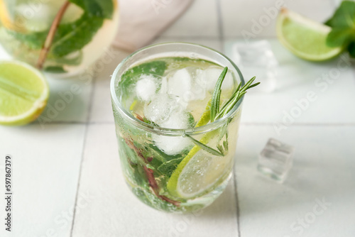 Glass of tasty mojito on light tile background