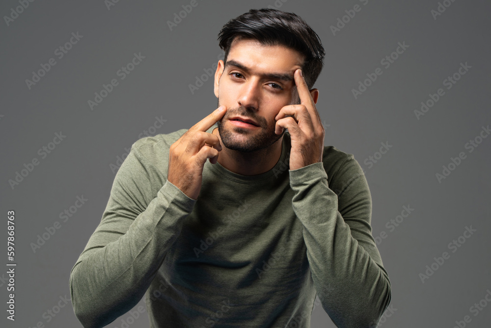 Portrait of young handsome Caucasian man touching and checking wrinkles on his face for skin care and beauty concepts, studio shot isolated on light gray background Portrait of young handsome Caucasian man touching and checking wrinkles on his face for skin care and beauty concepts, studio shot isolated on light gray background