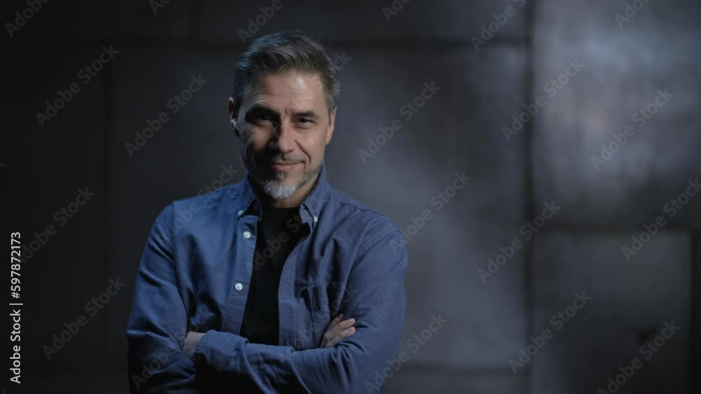 Portrait of happy mature casual man, smiling, standing in front of dark loft wall. Older, middle aged, mid adult, man in his 40s or 50s in shirt. Portrait of happy mature casual man, smiling, standing in front of dark loft wall. Older, middle aged, mid adult, man in his 40s or 50s in shirt.