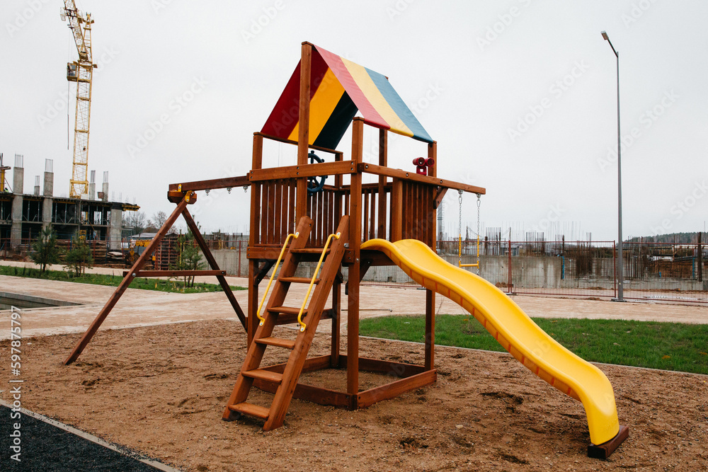 Children colorful playground near construction site apartment complex