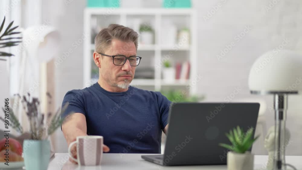 Entrepreneur managing business online with laptop computer at home. Businessman working in home office. Portrait of mature age, middle age, mid adult man in 50s browsing internet. Entrepreneur managing business online with laptop computer at home. Businessman working in home office. Portrait of mature age, middle age, mid adult man in 50s browsing internet.