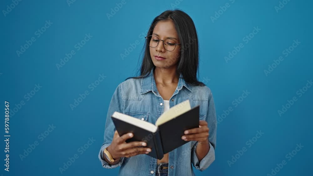 African american woman reading book looking upset over isolated blue background African american woman reading book looking upset over isolated blue background