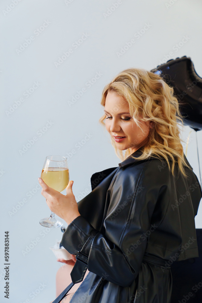 an attractive blonde in a black leather coat with a glass of champagne. an attractive blonde in a black leather coat with a glass of champagne.