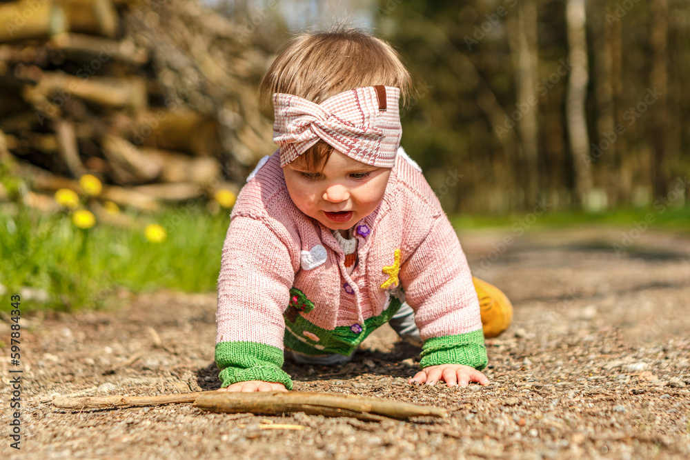 A cute little baby girl playing lost in thought in spring in a forest outdoors A cute little baby girl playing lost in thought in spring in a forest outdoors