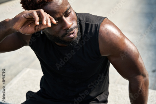 Canvastavla Fit sporty young African man wearing black sportswear relaxing after workout in urban park on summer day