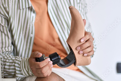 Man amputee with disability or amputation holding artificial foot leg prosthesis in hands. People with amputation disabilities mobility and health care rehabilitation concept  close up view.