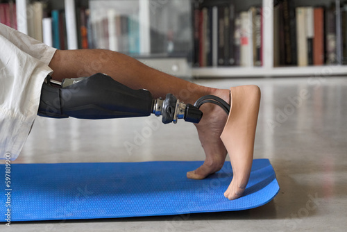 Sporty fit young man amputee with prosthetic leg disability prosthesis doing plank exercise on mat at home. Inclusive sport training for people with disabilities concept. Close up shot