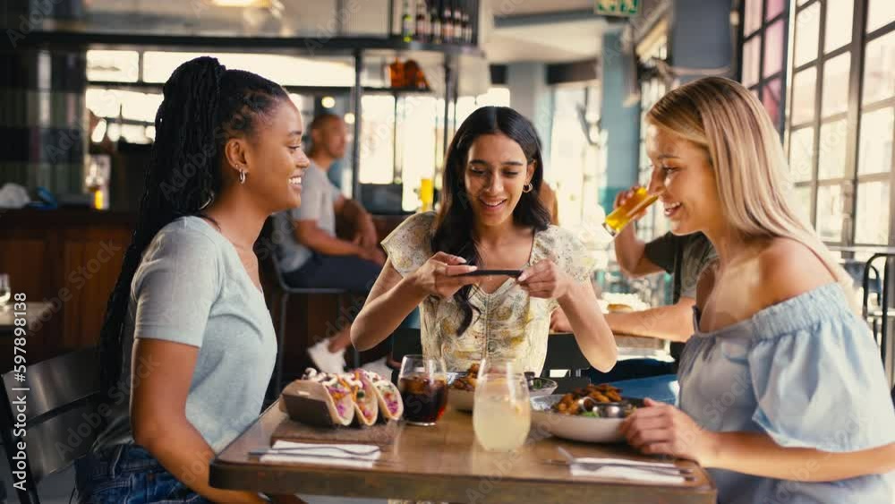 Group of multi-cultural female friends meeting in restaurant taking photo of food on mobile phone and posting to social media - shot in slow motion Group of multi-cultural female friends meeting in restaurant taking photo of food on mobile phone and posting to social media - shot in slow motion