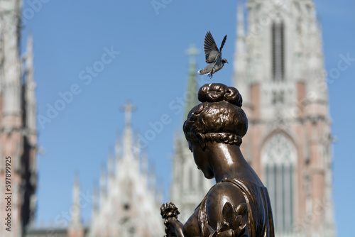 Paloma volando lista para apoyarse sobre cabeza de una escultura al aire libre