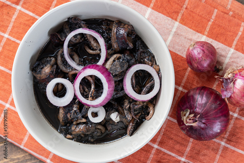 a tasty Filipino squid dish that uses Adobo method, also known as adobong pusit with a hint of spiciness topped with fresh red onions photo