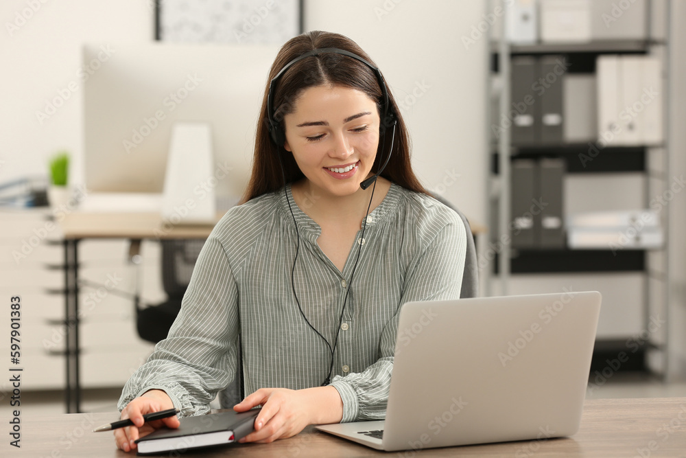 Hotline operator with headset and notebook working in office Hotline operator with headset and notebook working in office