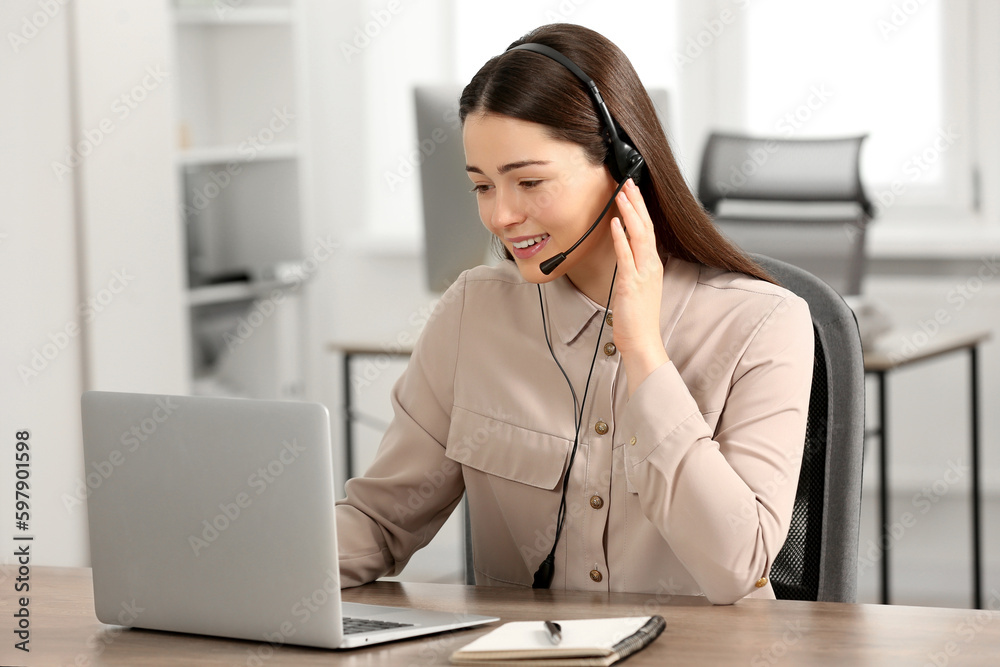 Hotline operator with headset working on laptop in office Hotline operator with headset working on laptop in office