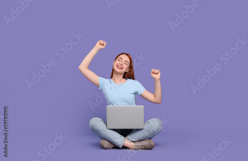Happy young woman with laptop on lilac background © New Africa