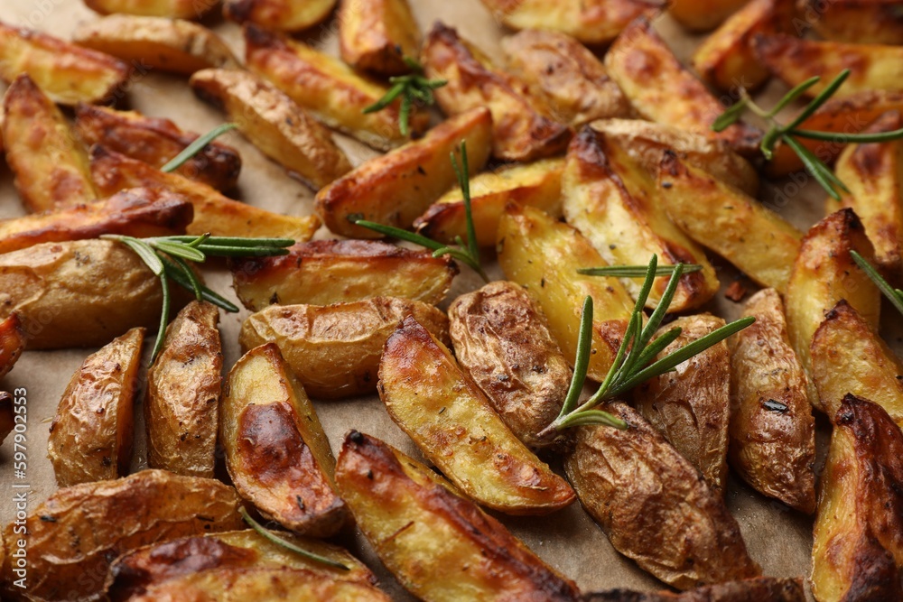 Tasty baked potato and aromatic rosemary on parchment paper, closeup Tasty baked potato and aromatic rosemary on parchment paper, closeup