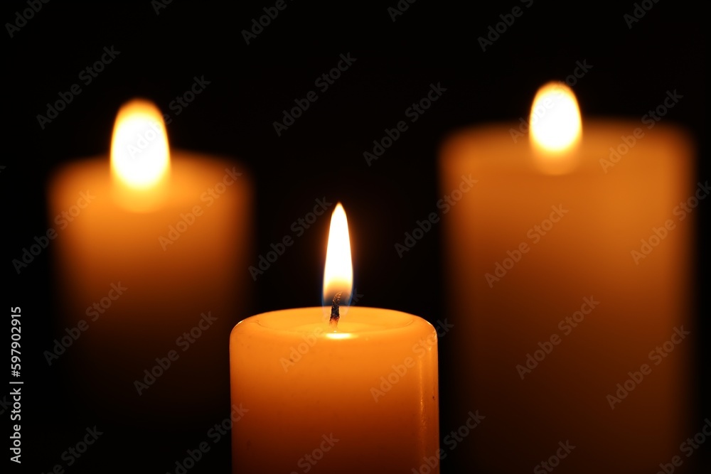 Burning wax candles on black background, closeup Burning wax candles on black background, closeup