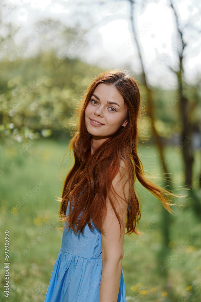 Portrait of a woman outdoors in spring in a blue dress looking at the camera, happiness outside, sunshine walk Portrait of a woman outdoors in spring in a blue dress looking at the camera, happiness outside, sunshine walk
