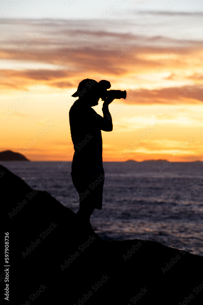 silhouette of a photographer with a beautiful sunrise in the background on Leblon beach in Rio de Janeiro.