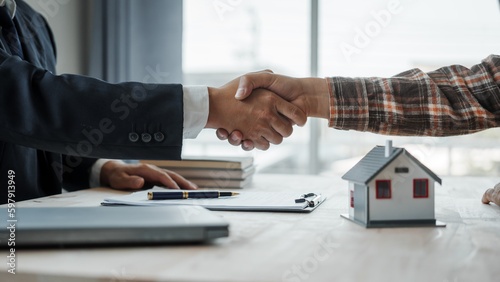 Shaking hands, Real estate agent with client considering buying a new home To pay a bribe to sign to approve the purchase, bribery concept.