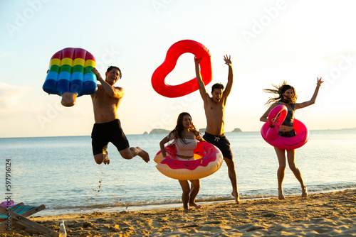 Group of diverse friends having fun swimming and jumping on the tropical summer beach
