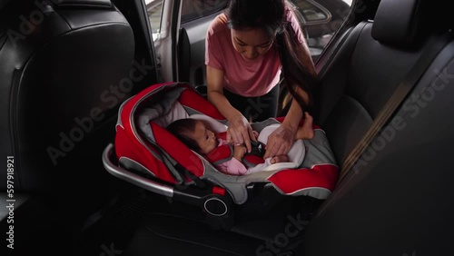 mother unbuckle safety belt and takes the baby out of the car seat photo