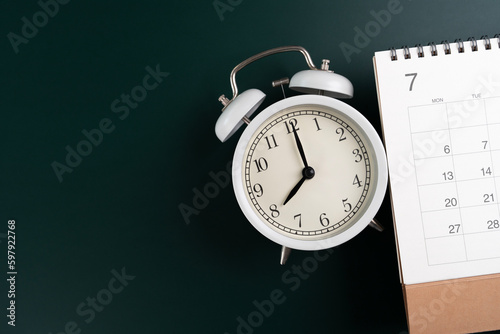 close up of calendar and alarm clock on the green table background, planning for business meeting or travel planning concept