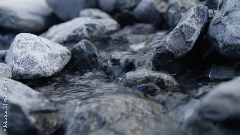 Water flows over frozen stones in a river in the Alps, Switzerland Water flows over frozen stones in a river in the Alps, Switzerland
