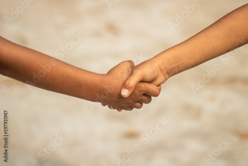 Two small people are shaking hands and the background is blurred © Rokonuzzamnan