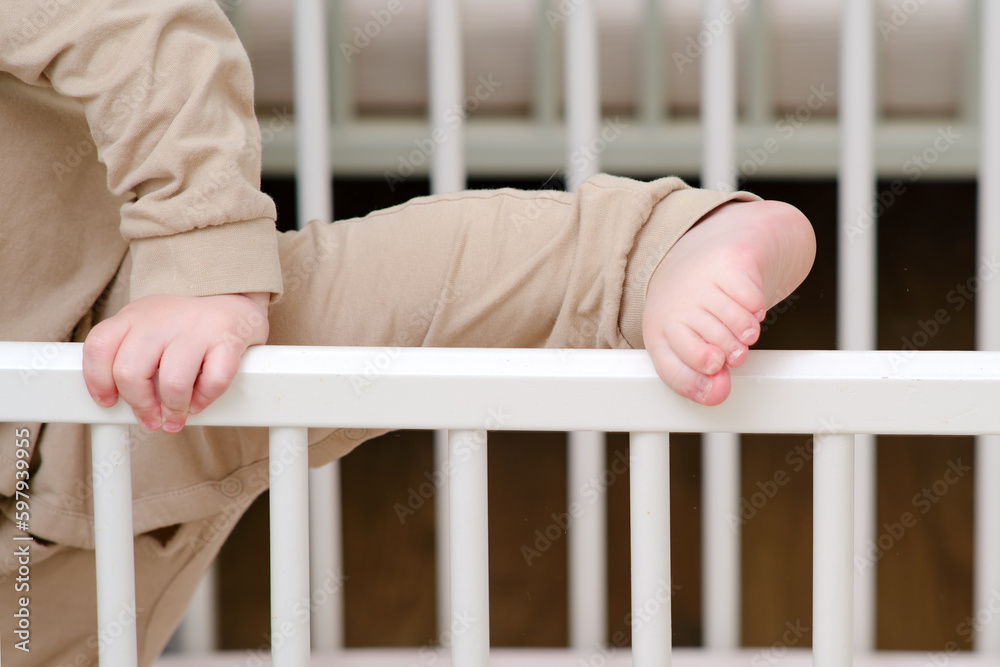 Baby escapes from the crib by climbing over the bars. The child climbs