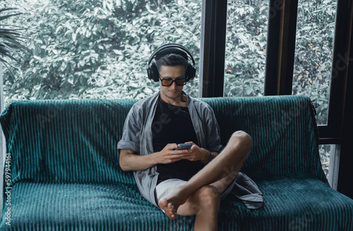 Handsome man call in smartphone, happy face, outdoor hipster portrait on the cafe, smile happy face, listen music on headphones, text, messenger, hipster, player,photo concept, laptop, coffee cup
