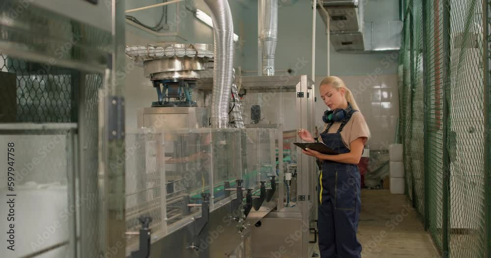 serious female engeener is working in laboratory experiment on pesticides, girl in uniform checking, counting quantity quality of canisters of pesticides agrochemicals, take notes in folder-tablet serious female engeener is working in laboratory experiment on pesticides, girl in uniform checking, counting quantity quality of canisters of pesticides agrochemicals, take notes in folder-tablet