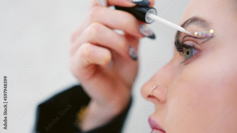 Woman attaching crystal make up with glue at the face Woman attaching crystal make up with glue at the face