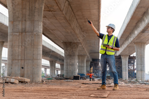 A civil engineer standing pointing at a road or expressway construction project under the road under construction. © tong2530