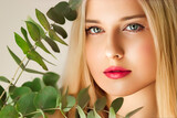 Beautiful woman and green leaves branch, blonde hair, red lipstick make-up face portrait, natural beauty and cosmetics
