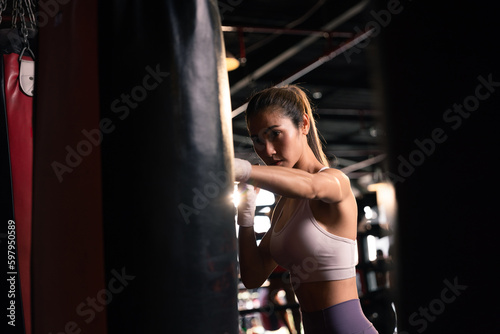 Beautiful female preparing bandages fighter trains in boxing at gym.