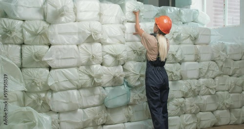 woman in special uniform taking sack, opening taking containers from it, checking control of goods industrier packing Plastic barrels which contain in factory lot of packed canisters stack of bottles