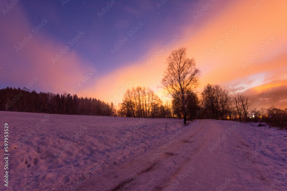 Evening winter scenery of snowy mountains and night city. the sky is illuminated by street lighting,
