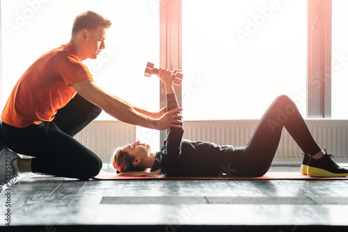 Young couple doing exercises with dumbbells at home.
