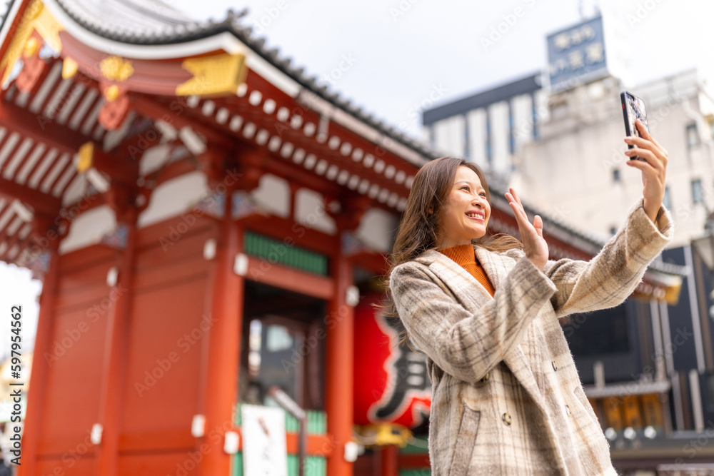Asian woman using mobile phone taking selfie during travel Sensoji Temple at Asakusa Tokyo, Japan in autumn. Attractive girl enjoy urban outdoor lifestyle travel city street on holiday vacation.
