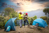 senior couple standing beside their tent on hill.