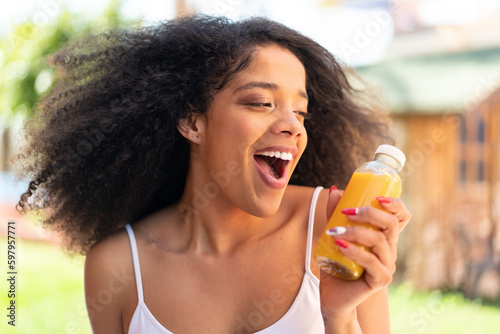 Young African American woman holding an orange juice at outdoors