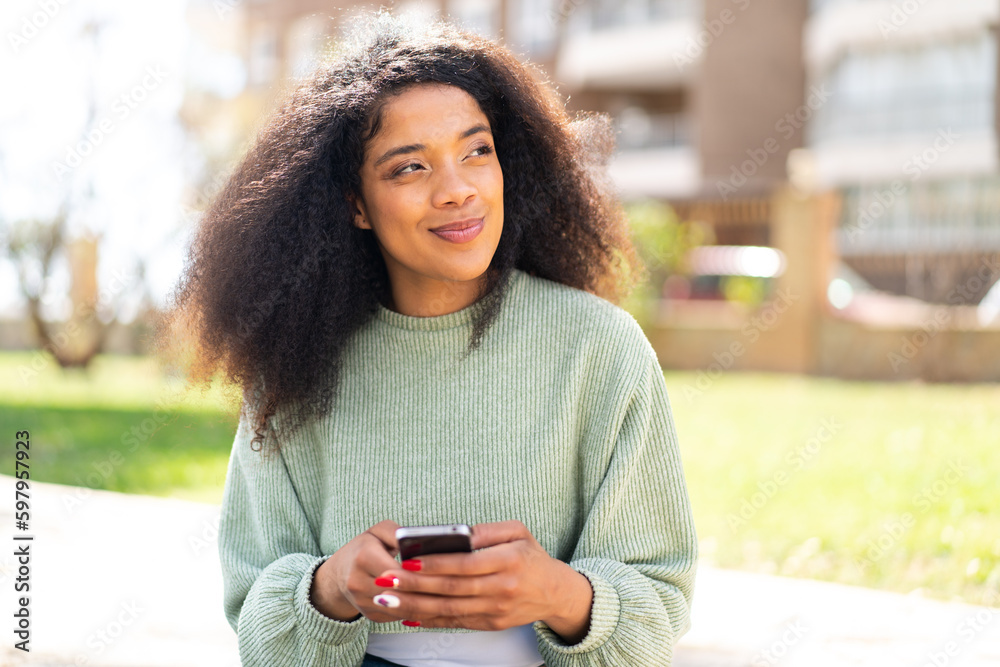 Young African American woman at outdoors using mobile phone