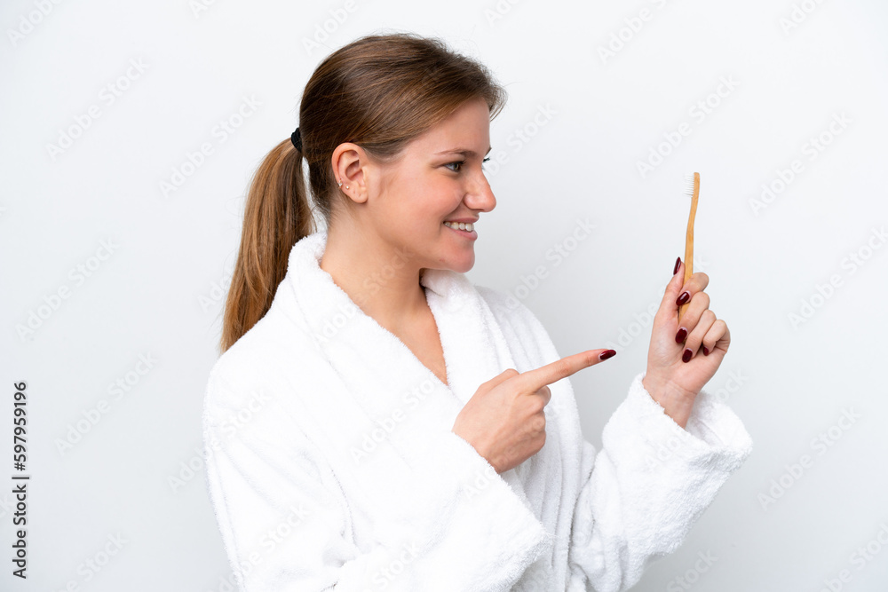 Young caucasian woman brushing teeth isolated on white background pointing to the side to present a product Young caucasian woman brushing teeth isolated on white background pointing to the side to present a product