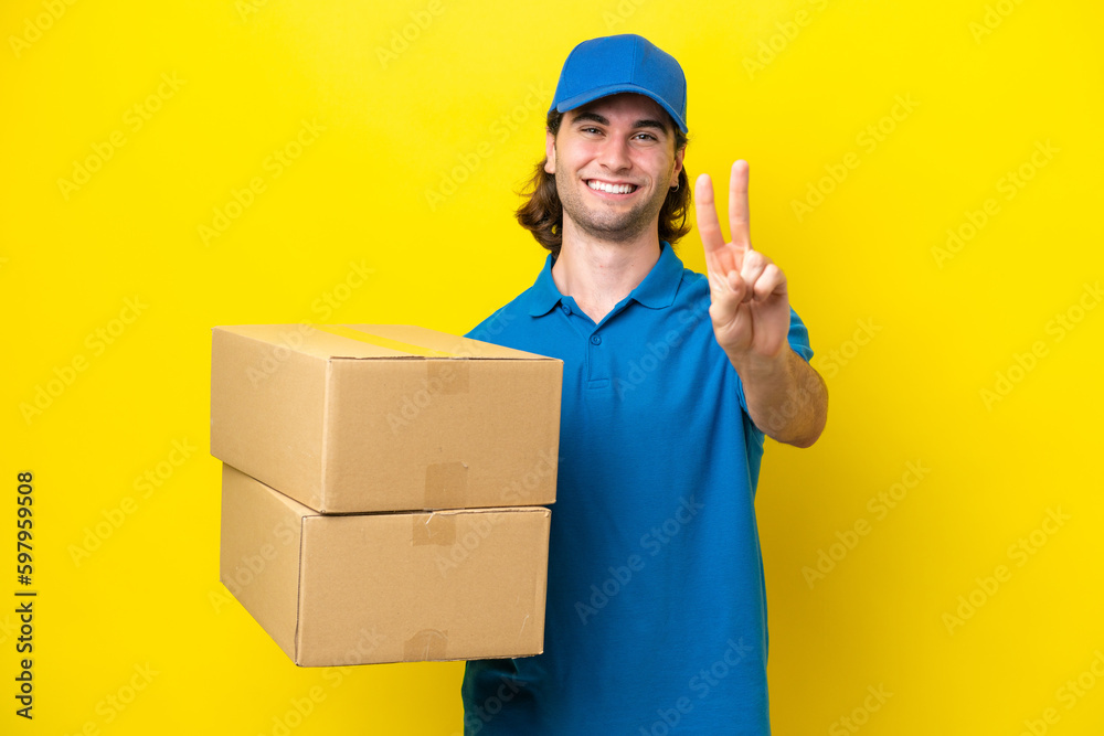 Delivery handsome man isolated on yellow background smiling and showing victory sign Delivery handsome man isolated on yellow background smiling and showing victory sign