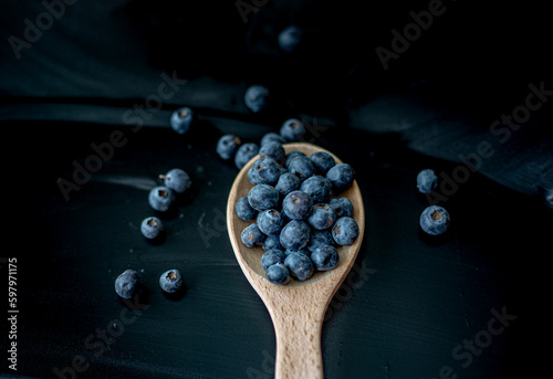 Fresh Blueberries in a wooden spoon on dark background, top view.