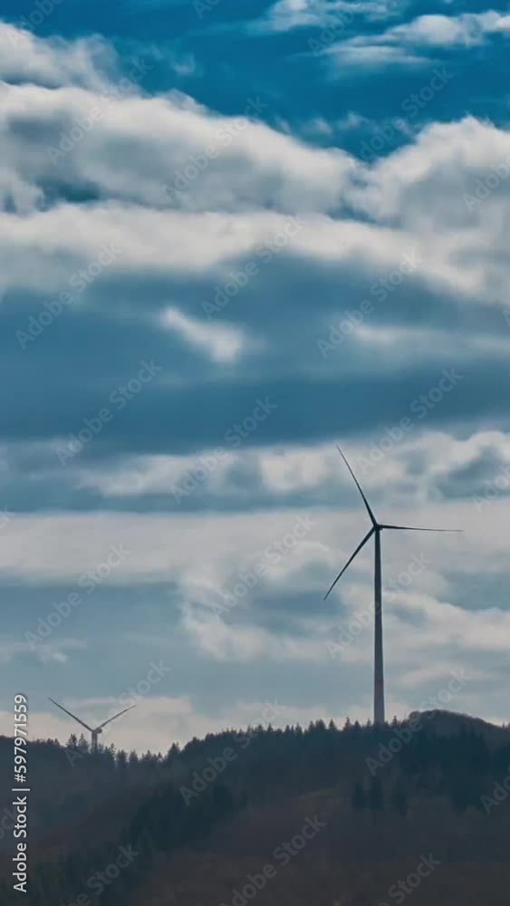 Wind power generators for electricity on a mountain in a vertical time-lapse recording Wind power generators for electricity on a mountain in a vertical time-lapse recording