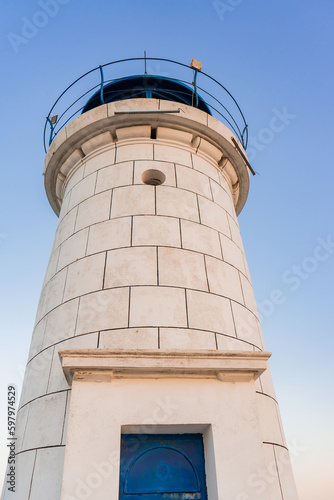 Bottom view of the Genoese lighthouse with a blue roof, from the pier formed of rocks, in a port on the Black Sea.